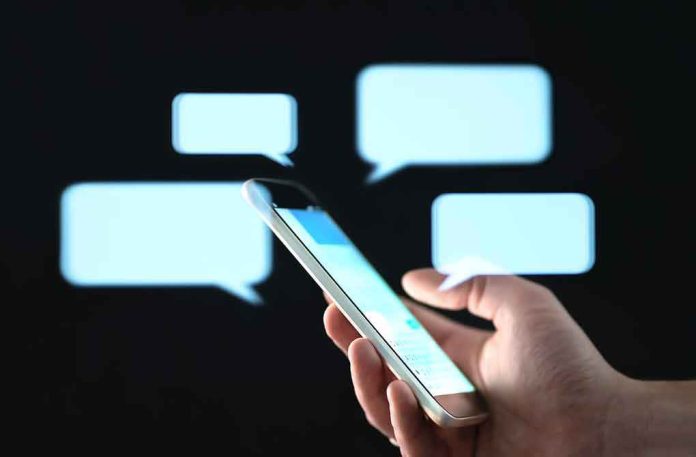 Hand holding smartphone with chat bubbles on dark background