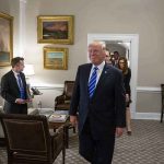 Donald Trump walks through an office with Sean Lawler nearby and Mariano Rajoy following behind