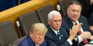 three men in suits seated at a conference table