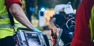 Paramedic with defibrillator beside patient on stretcher