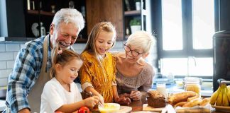 Grandparents and two children cooking together in a bright kitchen