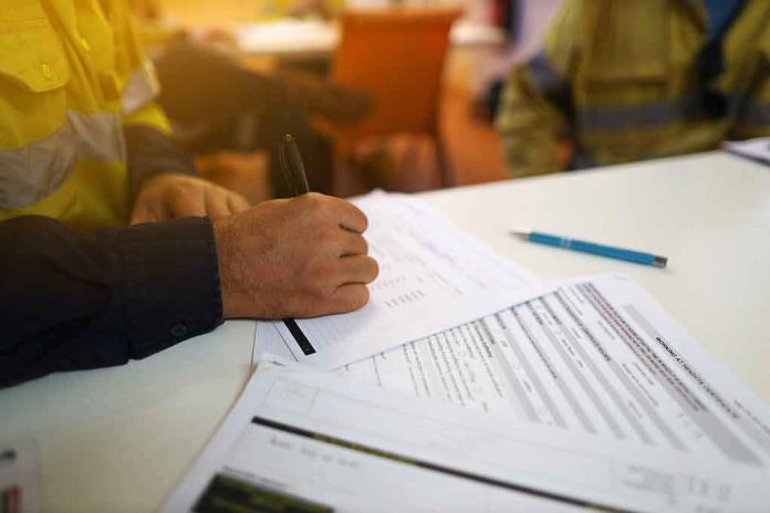 Worker hand filling out forms on a desk