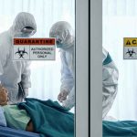 Healthcare workers in hazmat suits treat a patient in a quarantine room