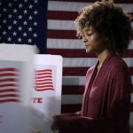 Election Fraud Charges PILE UP Across America Voter at a polling booth with an American flag backdrop