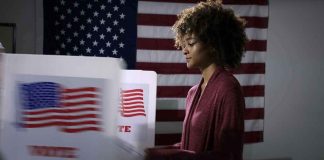 Voter at a polling booth with an American flag backdrop