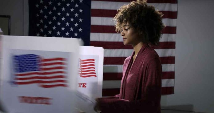 shutterstock_1737374753 Voter at a polling booth with an American flag backdrop