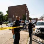 Citywide Panic: Gunman Triggers Lockdown Police officers secure an urban street with yellow tape near patrol cars