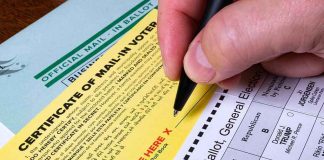 Hand signing a mail-in ballot certificate with pen