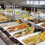 A buffet table displaying a variety of colorful dishes and salads