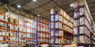 Warehouse aisles with tall blue and orange pallet racks filled with boxes