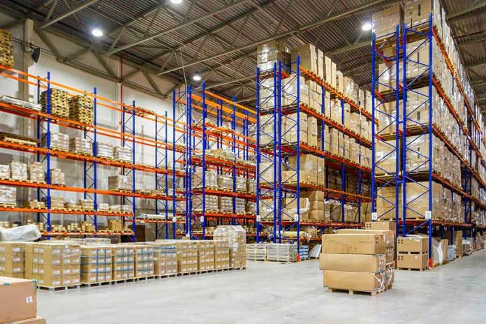 shutterstock_1929800966 Warehouse aisles with tall blue and orange pallet racks filled with boxes