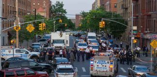 Police vehicles and officers block a city street during an active scene