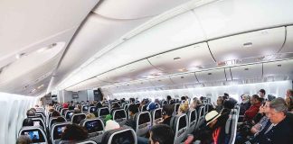 Airplane cabin with passengers seated in economy class
