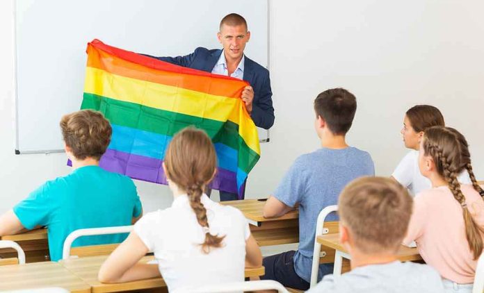 Teacher holding a rainbow pride flag in front of students