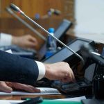 Fauci Held In Contempt Over Silence In COVID Hearing Person pressing a button on a conference microphone panel