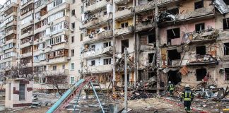 Damaged apartment building behind a playground slide
