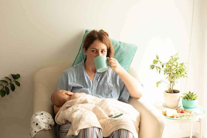 shutterstock_2135823883 Mother nursing baby while drinking from a mug in a cozy chair