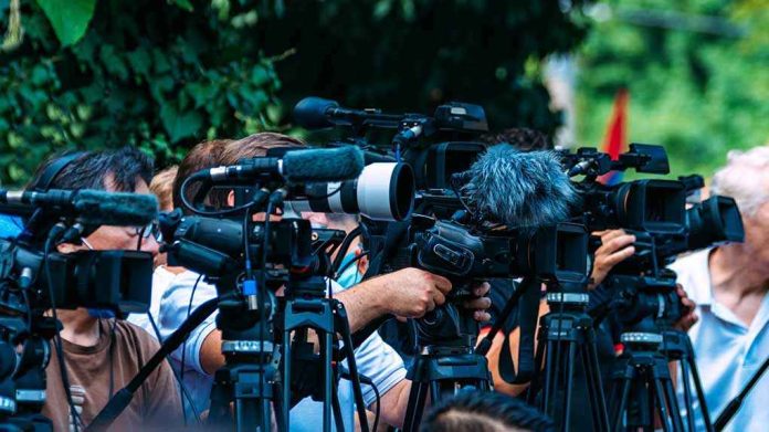 shutterstock_2210577723-3 TV news cameras crowding together at an outdoor event