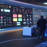 J6 Rioter Lands Pentagon Post cybersecurity operations room with large data dashboards and people discussing