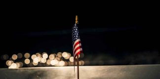 Small American flag on a memorial with bokeh lights at night