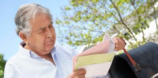 Older man checking mail at a rural mailbox