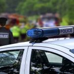 Police car with blue light bar at roadside scene