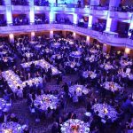 Ballroom filled with round tables at a formal gala dinner