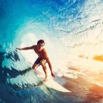 Surfer riding inside a blue wave barrel at sunrise
