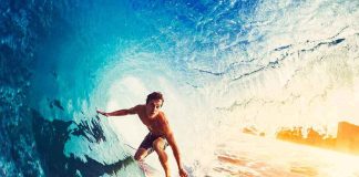 Surfer riding inside a blue wave barrel at sunrise