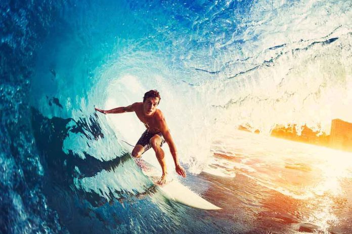 shutterstock_345007313 Surfer riding inside a blue wave barrel at sunrise