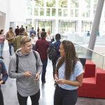 Students walking and talking in a bright campus atrium