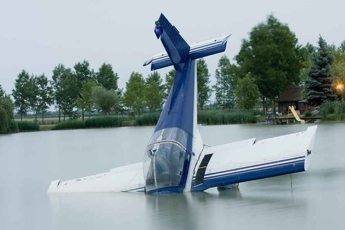 A submerged airplane partially in a lake with trees in the background
