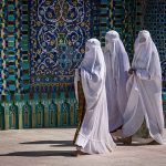 Church of England Hosts Islamic Fashion Show Three women in white veils walking past ornate blue tilework