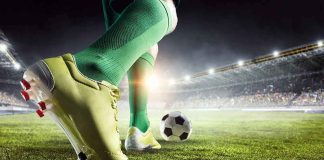 Soccer player in green socks about to kick a ball on a stadium field