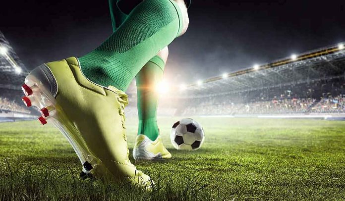 Soccer player in green socks about to kick a ball on a stadium field