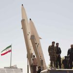 Generals Grab Power? Tehran Scrambles Soldiers stand beside large missiles at an outdoor display