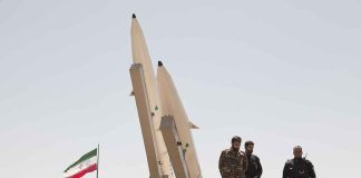 Soldiers stand beside large missiles at an outdoor display