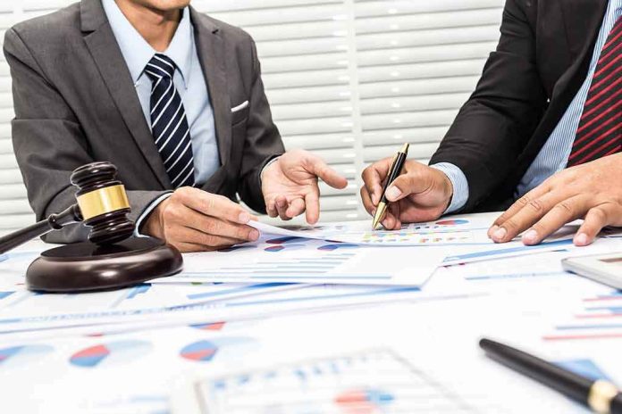 Two businesspeople in suits reviewing charts at a desk with a gavel
