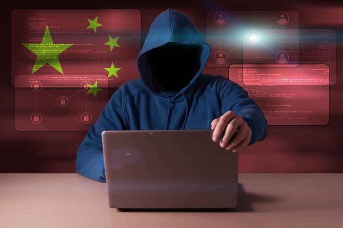 Hooded figure using a laptop with red cybersecurity graphics