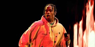 Performer in a hoodie holding a microphone on stage