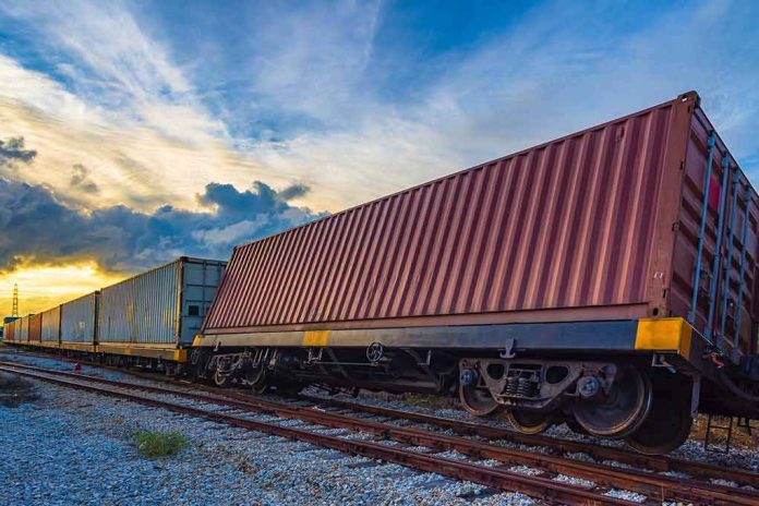 Freight train with shipping containers on tracks at sunset