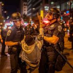 435 ARRESTED in Violent Crime Sweep Police officers detain a protester at night on a city street