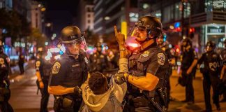 Police officers detain a protester at night on a city street