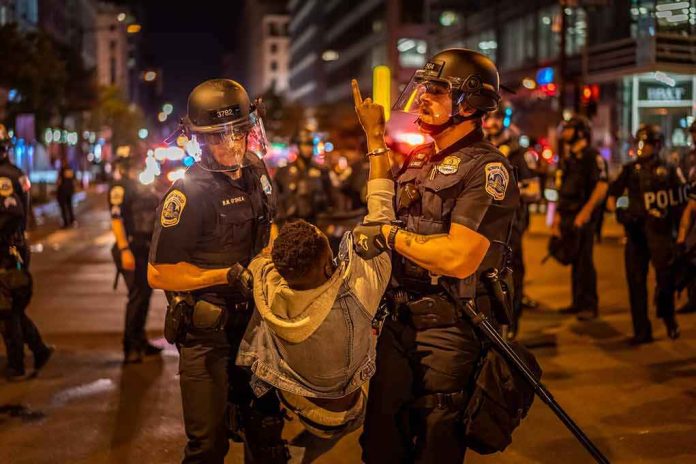 shutterstock_1746634547 Police officers detain a protester at night on a city street