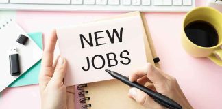 hands holding a note card over a desk with new jobs written on it