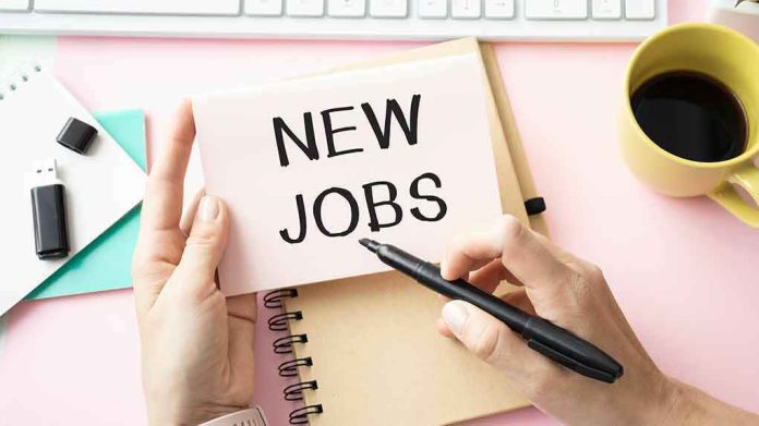 hands holding a note card over a desk with new jobs written on it