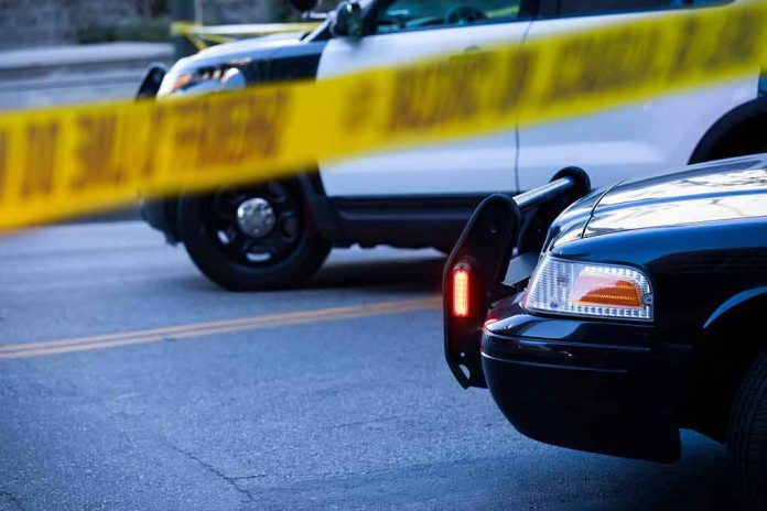 shutterstock_2097855037 Police cars behind yellow caution tape at a street scene