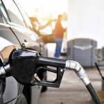 Why Your Fuel Bills Won’t Get RELIEF Anytime Soon Gas pump nozzle fueling a black car at a station