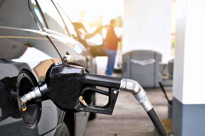 shutterstock_2272661533-1 Gas pump nozzle fueling a black car at a station