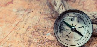 Compass on an old world map with rope and nautical charm